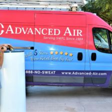 Advanced Air tech with a tank water heater next to a service van